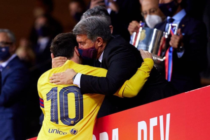 Messi i Joan Laporta es fonen en una abraçada quan el capità barcelonista es disposa a recollir la copa que es veu al fons.