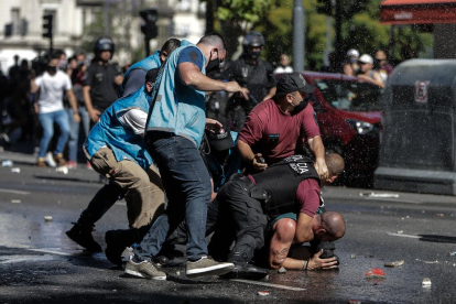 Policías argentinos reducen a un aficionado, durante la caótica despedida a Maradona en Buenos Aires.