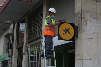 Un operari col·locant el logotip de CaixaBank a l'oficina situada al número 116 de la Rambla del Poblenou de Barcelona, anteriorment una oficina de Bankia.
