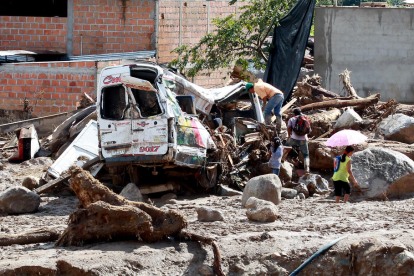 Habitants del barri San Miguel observen un vehicle destruït.