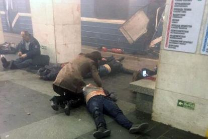 Una dona intenta socórrer una de les víctimes del brutal atemptat al metro.
