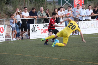 Un jugador del EFAC Almacelles pasa el balón ante la atenta mirada de un contrario y del colegiado.