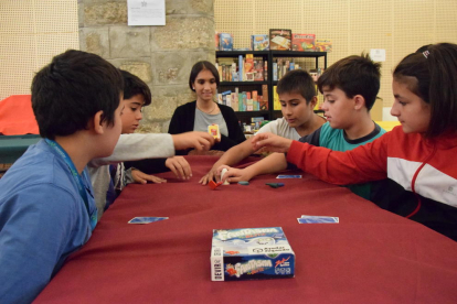 Nens jugant a un dels jocs de taula (esquerra) i altres participants escollint entre les múltiples propostes.
