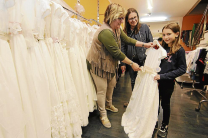 Una niña observa vestidos de comunión en la tienda Lianes del Eix Comercial.