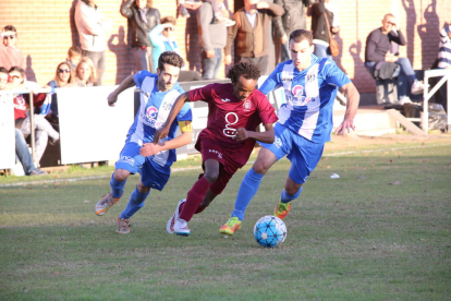 Un jugador de l’Agramunt avança amb perill davant la pressió de dos jugadors del Torregrossa.