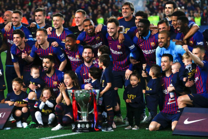 La plantilla del FC Barcelona posa con el trofeo de la Liga que esta temporada fue entregado al campeón el mismo día en que ganó el título.