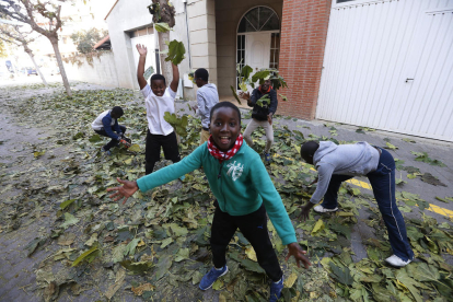 Niños jugando con las hojas caídas en las calles de Alcarràs.