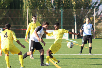 Un futbolista del Vallfogona intenta avançar entre jugadors de l’Agramunt.