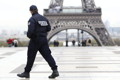 Un agente de policía patrulla frente a la Torre Eiffel.