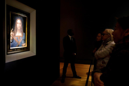 Varias personas contemplan el cuadro “‘Salvator Mundi” del Leonardo.