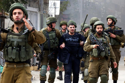 Soldados israelíes con un manifestante palestino detenido, ayer, en Hebrón.