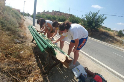 Un grupo de jóvenes repintando bancos en mal estado de esta localidad de la Vall del Corb. 