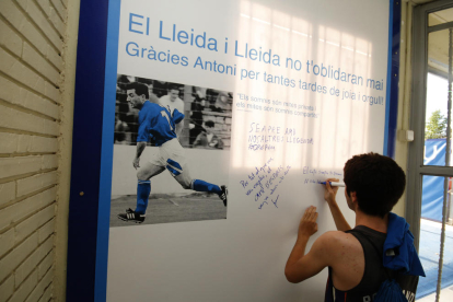 Un aficionado escribe un mensaje de recuerdo en el mural dedicado a Antoni Palau.