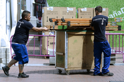 Imagen de dos operarios transportando material a la salida de una empresa.