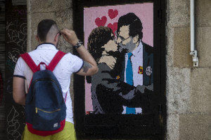 Un artista urbano pinta a Rajoy y Puigdemont besándose cerca de la Generalitat