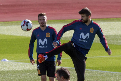 Gerard Piqué golpea el balón ante Saúl Ñíguez ayer durante el entrenamiento de la Selección.
