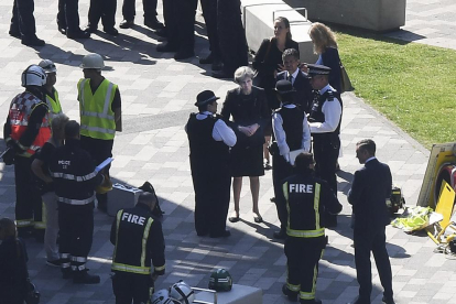 La primera ministra Theresa May conversa amb agents de la policia britànica a la zona de l’incendi.