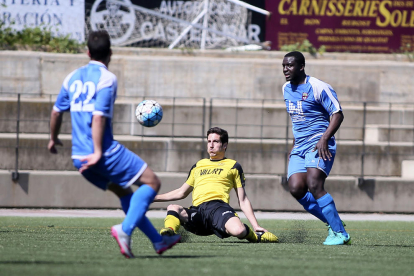 Un jugador del Balaguer despeja un balón ante la proximidad de dos jugadores rivales.