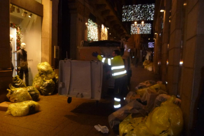 Operaris recullen les escombraries que els comerciants deixen a les portes dels comerços de l’Eix.