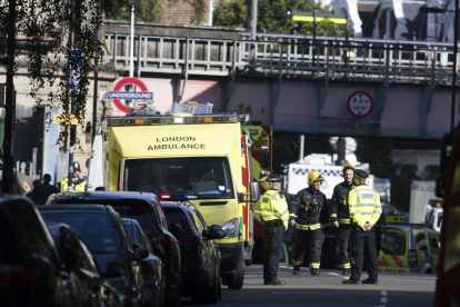 Una agent de policia escorta una ferida en l’atac al metro de Londres ahir.