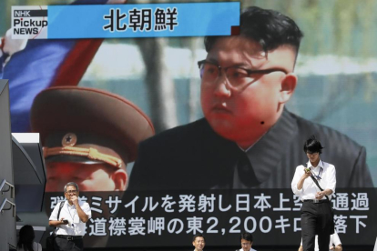 Vianants caminant sota un monitor que mostra el líder nord-coreà, Kim Jong-un, ahir.
