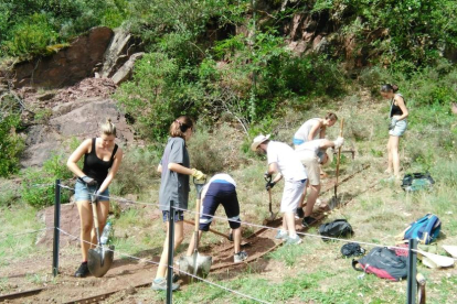 A la izquierda, voluntarios del campo de trabajo del Pallars en el camino a la mina de Castell-estaó, en la Vall Fosca. Sobre estas líneas, excavación en el yacimiento de Gebut.