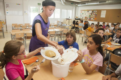 Els alumnes llancen en un cubell el menjar que els ha sobrat.