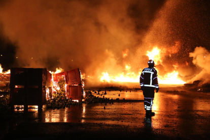 Un bombero, ante las llamas en el exterior de esta empresa situada en las afueras del barrio de Pardinyes.