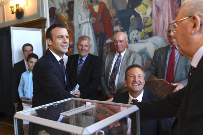 El president de França, Emmanuel Macron, saluda la mesa electoral després d’haver emès el vot.