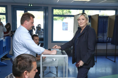 El presidente de Francia, Emmanuel Macron, saluda a la mesa electoral tras haber emitido su voto.
