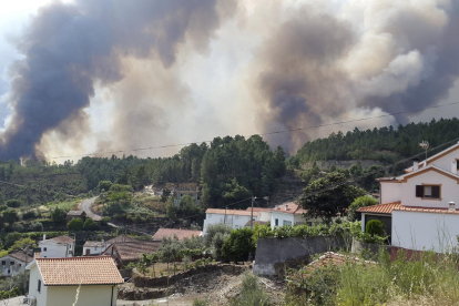 Vista del humo y las llamas cerca de las viviendas en la localidad de Cabreira, en Gois.