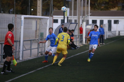 Un jugador del Lleida Esportiu B pugna con el balón ante uno del Vila-Seca bajo la atenta mirada del asistente arbitral.