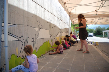 Diversos nens en una de les activitats infantils, pintar un mural a l’exterior de la Dinosfera.