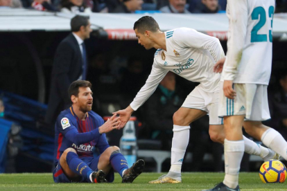 Cristiano Ronaldo ajuda a aixecar-se Messi, figura del Barça.