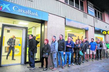 Colas de clientes para sacar dinero en una sucursal de Caixabank, ayer en Tàrrega.