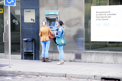 Colas de clientes para sacar dinero en una sucursal de Caixabank, ayer en Tàrrega. 