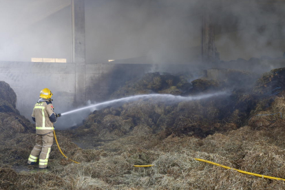 Un bomber apagant ahir l’incendi a l’interior de la granja.