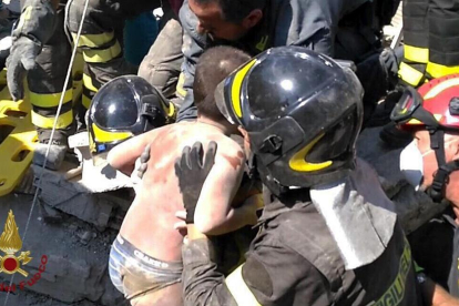 Los bomberos rescatan a un pequeño atrapado en los escombros tras el terremoto en la isla de Isquia.