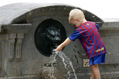 Un niño juega con el agua de una fuente.