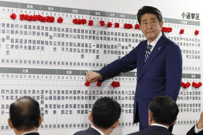 El primer ministro japoné, Shinzo Abe, pone un pin en forma de rosa en el nombre de los candidatos. 