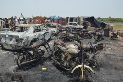 Coches y motos calcinados en el lugar donde explotó el camión cargado de gasolina en Pakistán.