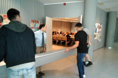 El momento del traslado de un banco al interior de una aula.