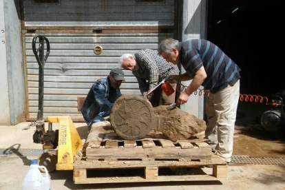Un grupo de tres voluntarios trabajando en la limpieza de una de las estelas funerarias de Sanaüja. 