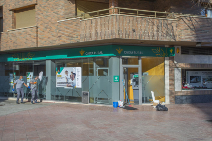 Los trabajadores de limpieza dan los últimos retoques a la nueva oficina de Caixa Rural en Lleida.