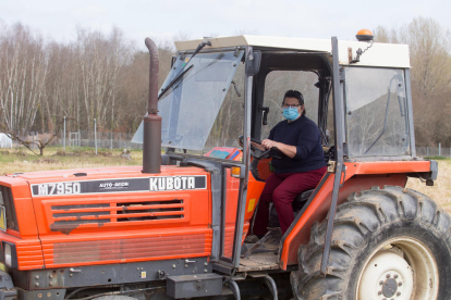 Una agricultora conduce el tractor en una explotación agrícola.