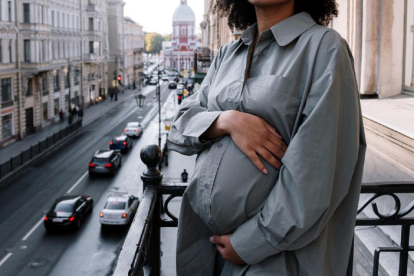Dona embarassada agafant-se la panxa al balcó d'un habitatge