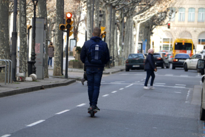 Un chico en patinete por el medio de los carriles para vehículos de Rambla Ferran, sin casco.