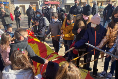 Niños y niñas de Castelldans golpeando al Tió durante la celebración de ayer.