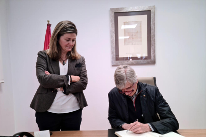 El conseller de Salut, Josep Maria Argimon, signant el llibre d'honor al Conselh Generau d'Aran, acompanyat de la síndica d'Aran,Maria Vergés.