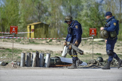 Dos soldats ucraïnesos marxen al costat de les restes de projectils detonats.